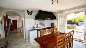 A kitchen with a dining table, chairs, and a black range hood.