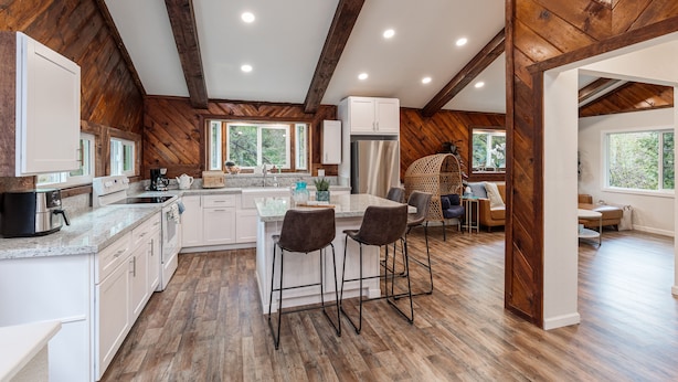Una cocina amplia con vigas de madera, una isla grande y taburetes de bar.