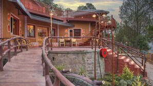 Un refugio rústico con escalera de madera, balcón y pared de piedra.