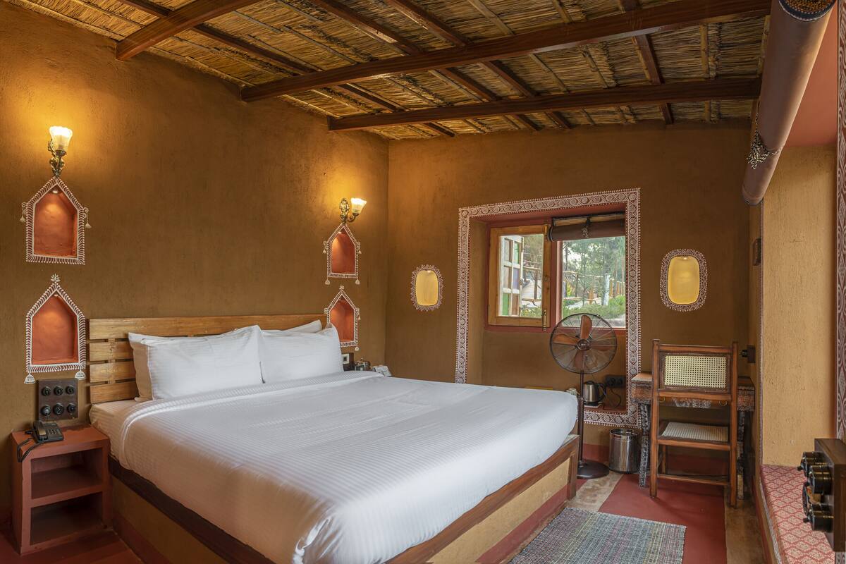 Una cama grande con ropa blanca, cabecera de madera y dos luces fijadas a la pared.