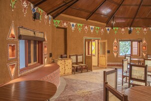 Une pièce avec un plafond en bois, un comptoir en briques et plusieurs chaises et tables en bois.