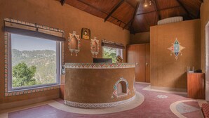 Una habitación con un ventanal grande, un mostrador de madera redondo y vistas a un paisaje montañoso.