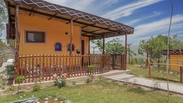 Un bâtiment à deux étages doté d’un porche couvert, d’une terrasse clôturée et d’un petit jardin avec un bassin.