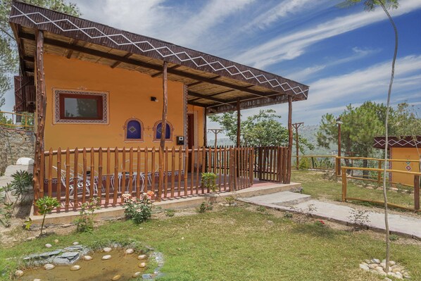 A two-story building with a covered porch, a fenced patio, and a small garden area with a pond. - A Kasauli Ggaon by Echor (Kasauli)