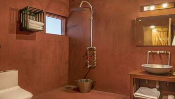 Een badkamer met douche, toilet, wastafel en een klein raam.