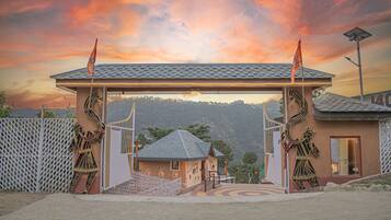 A building with a covered entrance, a small adjacent structure, and a decorative fence.