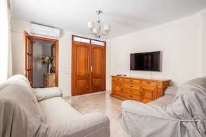 A room with a sofa, a wooden cabinet, a television, and a door.
