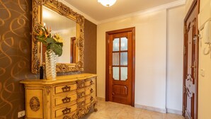 Un pasillo con un espejo grande y decorativo, una puerta de madera y un muro con diseño geométrico.