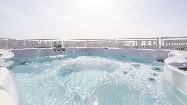 Un área de hidromasaje con varias tinas, una piscina y una cerca blanca.
