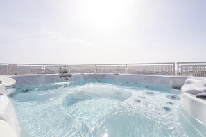 A hot tub area with multiple tubs, a pool, and a white fence.