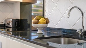 A kitchen with a bowl of fruit on the counter, a modern faucet, and a tiled backsplash. - Holiday Apartment "Veleta ll" close to Beach with Sea View, Shared Pool & Wi-Fi (Pollença)