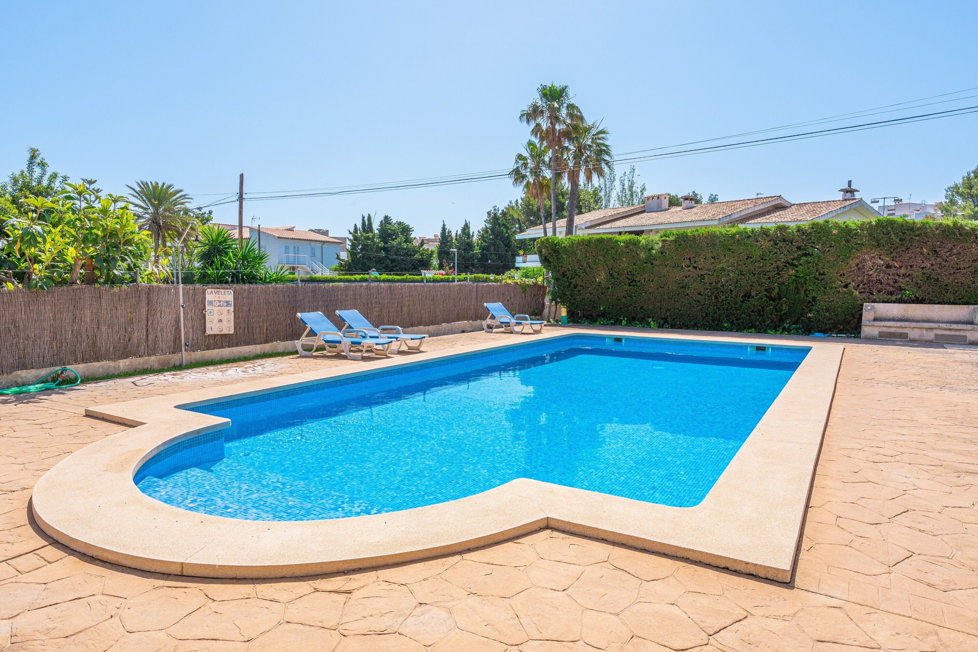 Une piscine rectangulaire à bords incurvés, entourée de chaises longues et d’une terrasse en pierre.