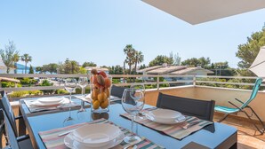An outdoor dining area with a table set for two, a glass of water, and a fruit bowl. - Holiday Apartment "Veleta ll" close to Beach with Sea View, Shared Pool & Wi-Fi (Pollença)