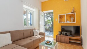 Ein Wohnzimmer mit einer Couch, einem Couchtisch, einem Fernseher und einem Balkon mit gelber Wand.