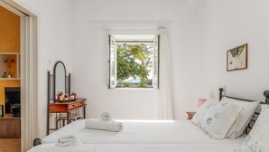 Ein Schlafzimmer mit einem Bett, einem Schreibtisch, einem Stuhl, einem Fenster und einem Spiegel.