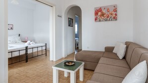 Ein Schlafzimmer mit einem Bett, einem kleinen Tisch mit einer Schüssel, einem Sofa und einem Gemälde an der Wand.