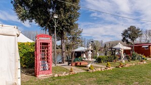 A red telephone booth, a white gazebo, and a statue in a garden setting.