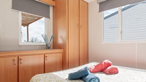 A bedroom with a bed, wooden wardrobe, and a window with blinds.