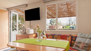 Een eethoek met een tafel, stoelen, een bank, een televisie en een raam met uitzicht.