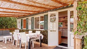 Een buitenontbijtplaats met een tafel, stoelen, een houten terras en een overdekte patio.