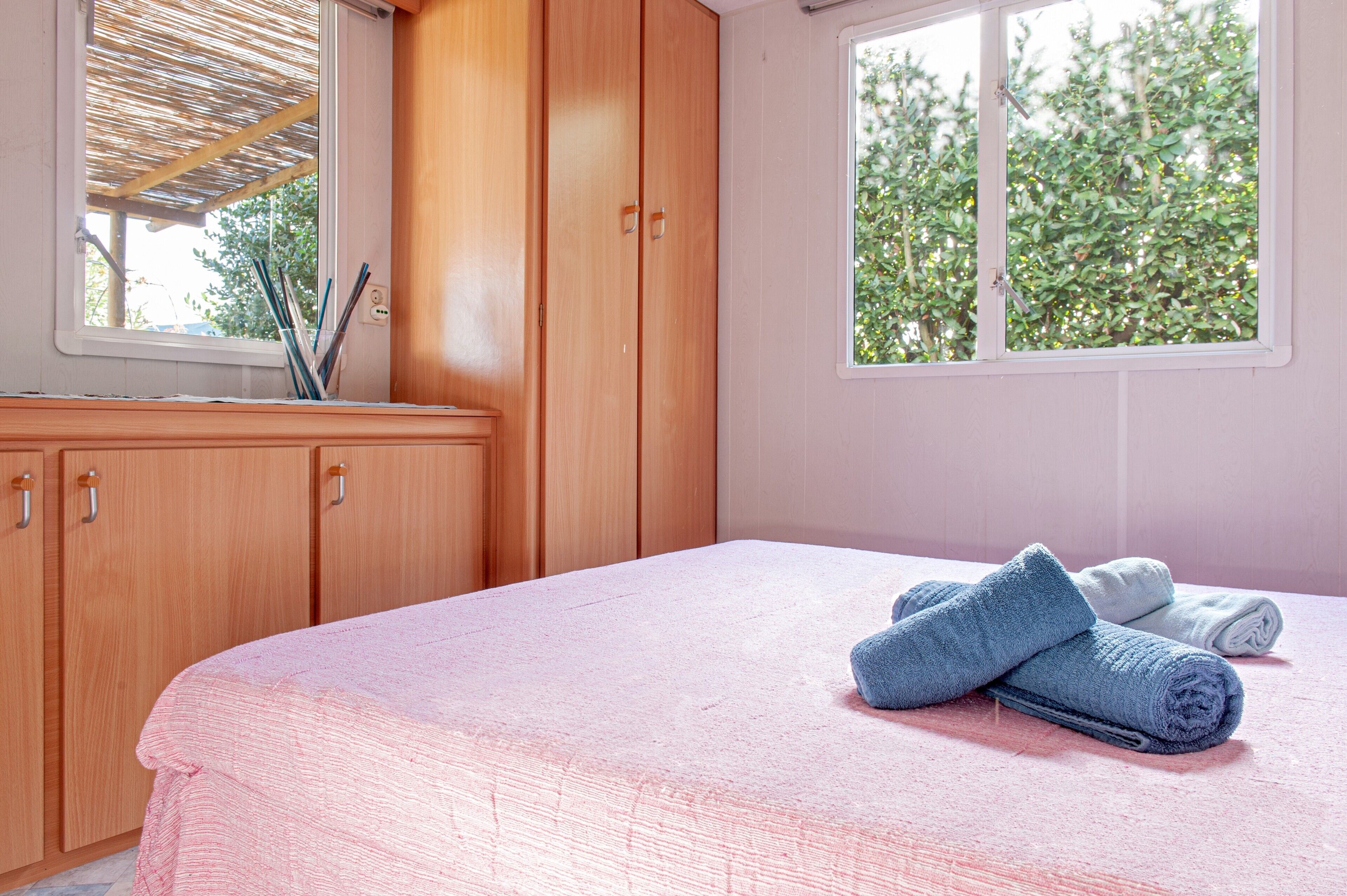 Une chambre à coucher avec un lit, une armoire en bois et une fenêtre donnant sur des arbres.