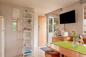 Eine Küche mit einem Holztisch, einem an der Wand montierten Fernseher und einer Tür, die auf einen Balkon führt.