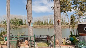 Een rustieke buitenruimte met een houten constructie, een metalen poort en een kleine brug over water.