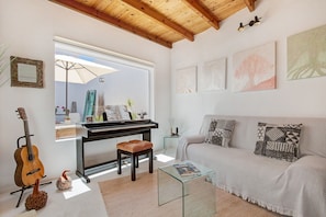 Ein Wohnzimmer mit einem Klavier, einem Sofa, einem Glastisch und einer Gitarre.