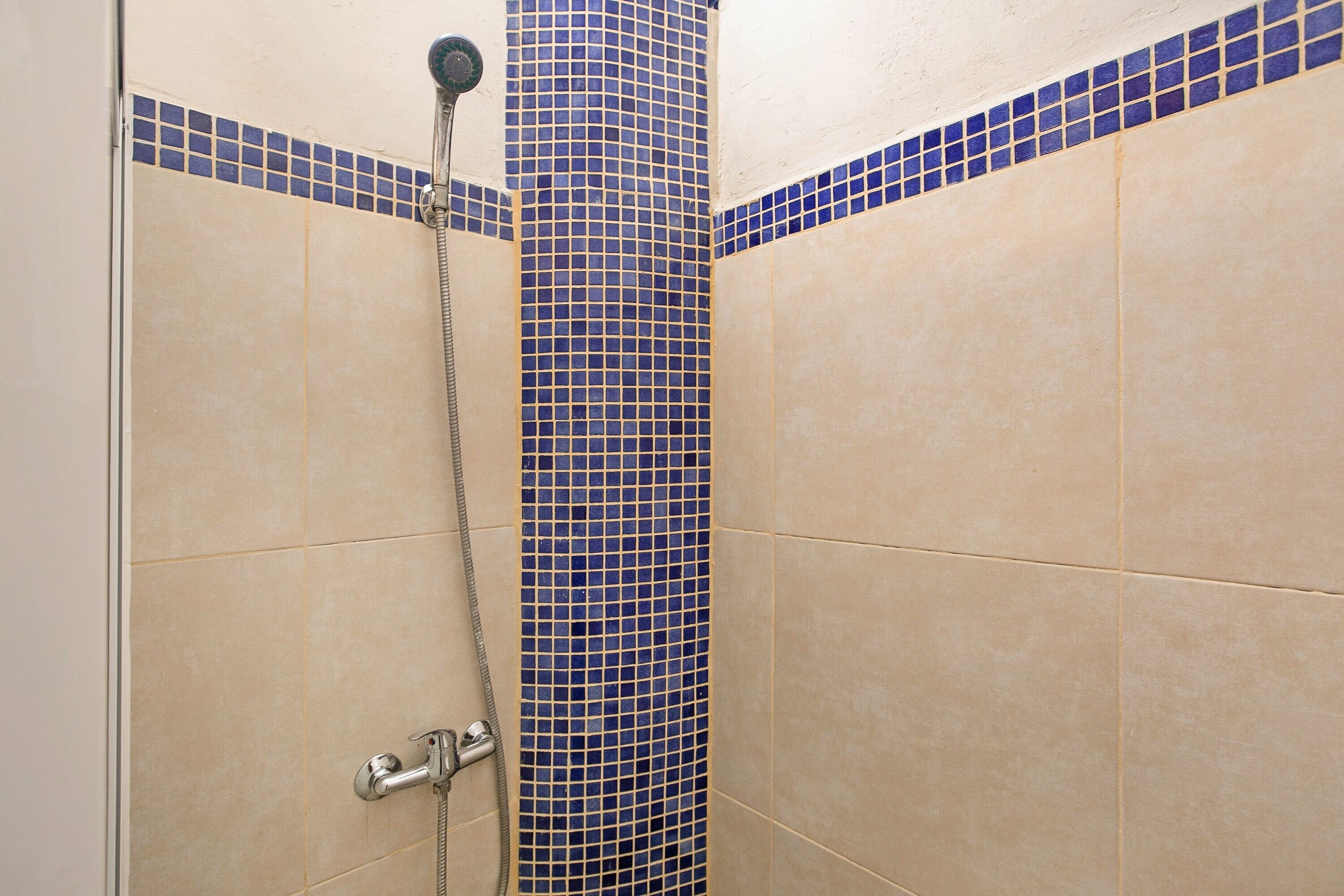 Eine Dusche mit einer blauen Säule aus Fliesen und beige gefliesten Wänden.