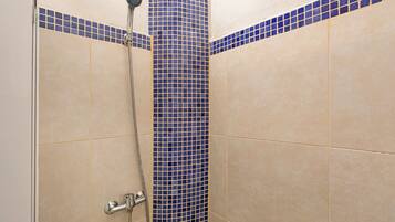 Eine Dusche mit einer blauen Säule aus Fliesen und beige gefliesten Wänden.