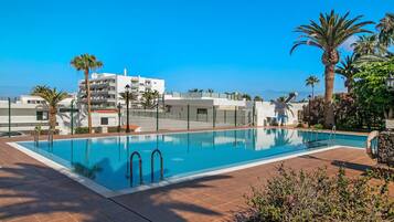 A rectangular swimming pool with a clear blue water surface, surrounded by a tiled deck area.