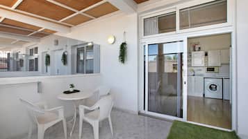 A modern interior with a dining area, a kitchen, and a sliding glass door leading to an outdoor space.