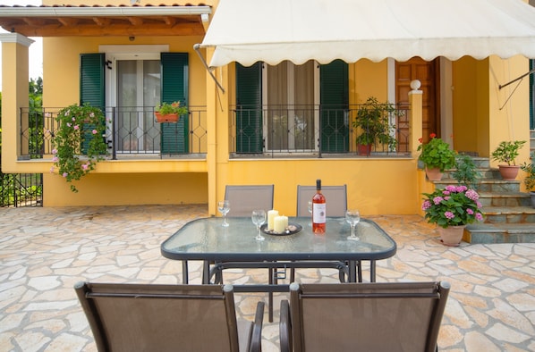 Une terrasse avec une table et des chaises, une bouteille de vin et des plantes en pot.