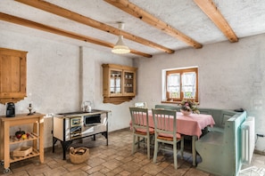 Una cocina rústica con vigas de madera, una estufa antigua y una mesa de comedor con sillas.