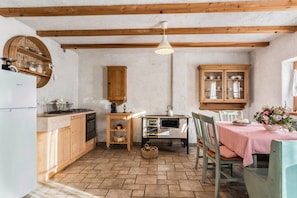 Una cocina con armarios de madera, una mesa de comedor con mantel a cuadros y una lámpara colgante.