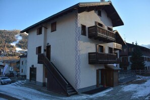 A multi-story building with balconies, a staircase, and a view of a snowy landscape.