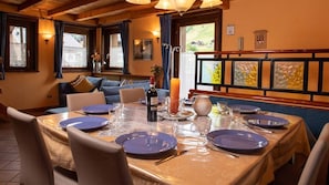 Un coin repas avec une table dressée pour quatre personnes, une bougie et une bouteille de vin.
