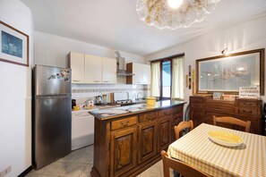 Une cuisine équipée d’un réfrigérateur en acier inoxydable, de meubles en bois, d’un four encastré et d’une nappe à carreaux.