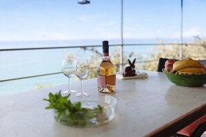Une table avec une bouteille de vin, deux verres, un saladier de fruits et une petite plante.