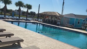 A swimming pool with lounge chairs and a thatched-roof structure. - Bikini Bottom: Close to pool, dining, beach, pets (Galveston)