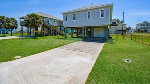 A two-story house with a covered porch and a concrete driveway. - Bikini Bottom: Close to pool, dining, beach, pets (Galveston)