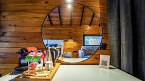 A room with wooden walls, a circular mirror, a minibar, a bed, and a window. - Dolce Vita Luxury Bungalows (Bodrum)