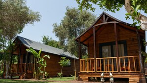 A wooden cabin with a porch and two gnome statues. - Dolce Vita Luxury Bungalows (Bodrum)
