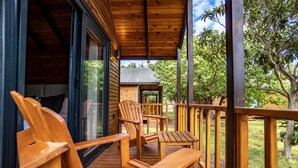 A wooden deck with seating and a glass door leading to a room. - Dolce Vita Luxury Bungalows (Bodrum)