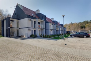 Ein modernes, mehrgeschossiges Wohngebäude mit rotem Ziegeldach, Balkonen und befestigter Auffahrt.