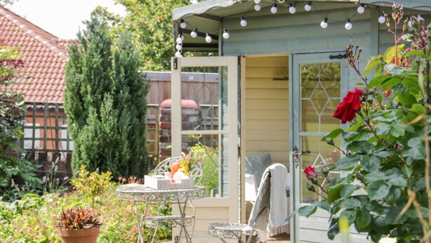 A small, open-sided structure with a table and chairs, surrounded by potted plants and flowers. - Bryn Offa Cottage (Holywell)