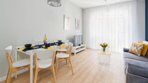 A modern living room with a dining area, featuring a sofa, TV, and a dining table with chairs.