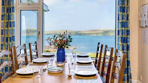 Mesa de comedor lista para seis personas con vista al mar.