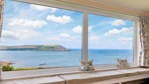 Una habitación con un amplio ventanal que ofrece vistas al mar y una isla distante.
