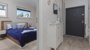 A bedroom with a bed, bedside table, nightstand, dresser, and a door.